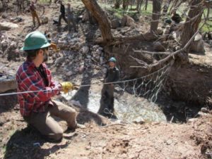 Volunteers install two steel nets into the channel of Pack Creek